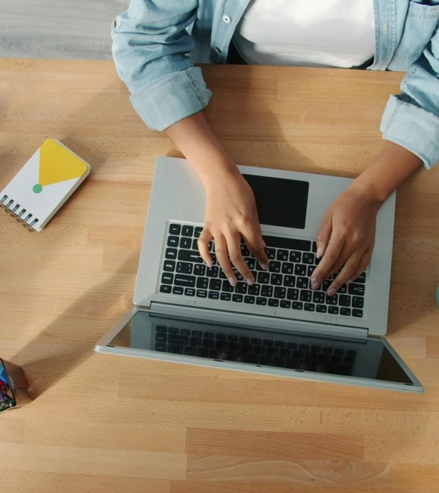 Top-down view of a person working on a laptop at a neat desk with accessories.